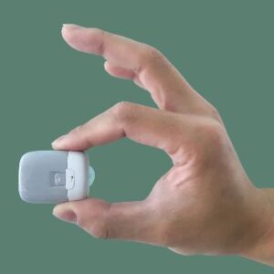 Рука тримає маленький пристрій Medtrum на зеленому фоні.